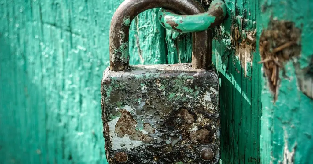 Datingfraude herkennen: een verroest hangslot aan een groene deur