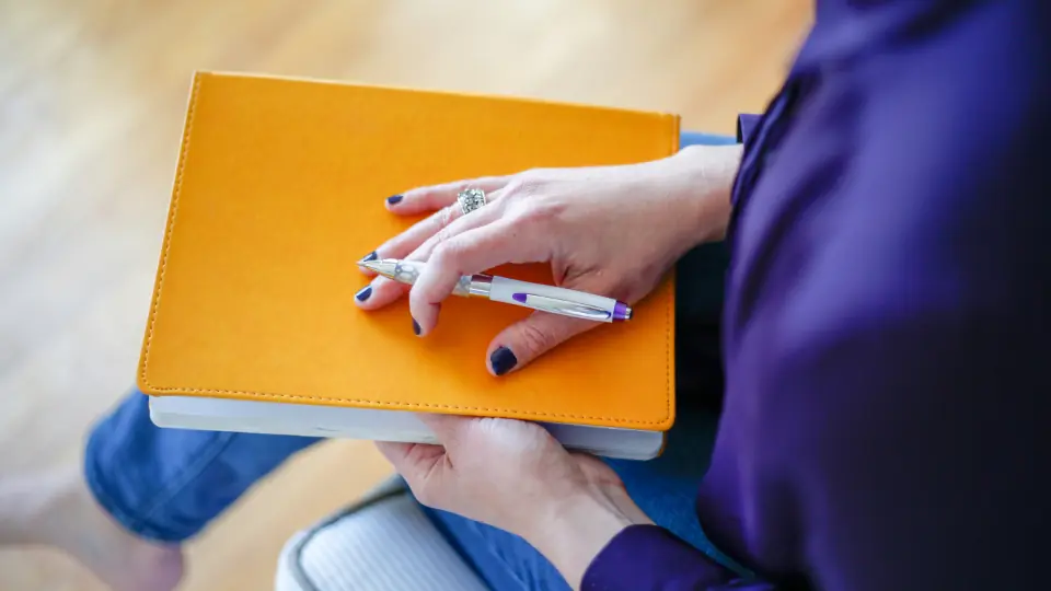 Tips voor je datingprofiel uitschrijven: iemand maakt notities in een oranje schrift