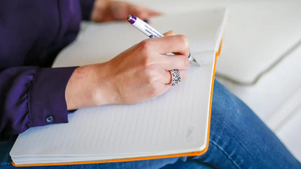Een eerste bericht bedenken: een hand met een pen boven een open notitieboek