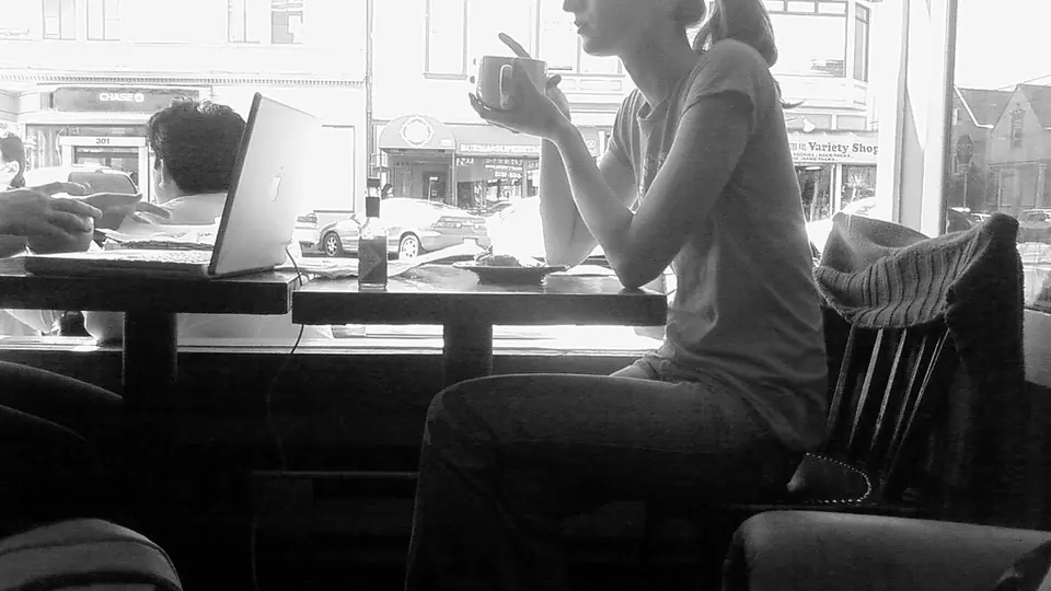 Een eerste date in een café: een vrouw zit met een kop koffie aan het raam