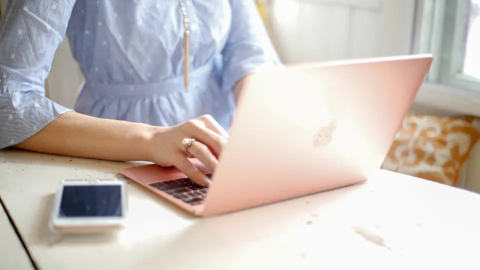 Veilig op datingsites: iemand typt op een laptop, met een smartphone ernaast