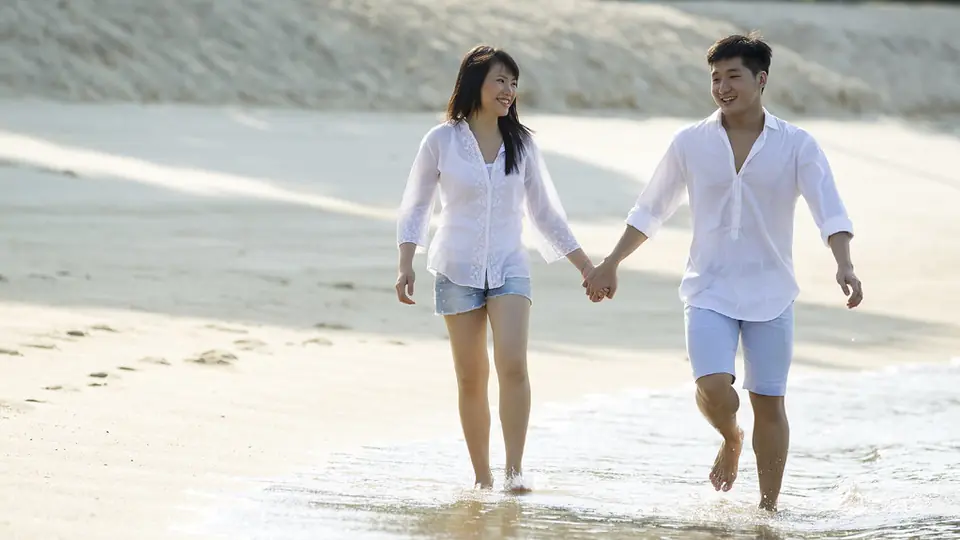 Van datingsites naar een eerste date: een koppel wandelt hand in hand over het strand