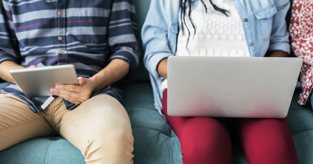 Datingapps: twee mensen zitten op een bank met een tablet en een laptop