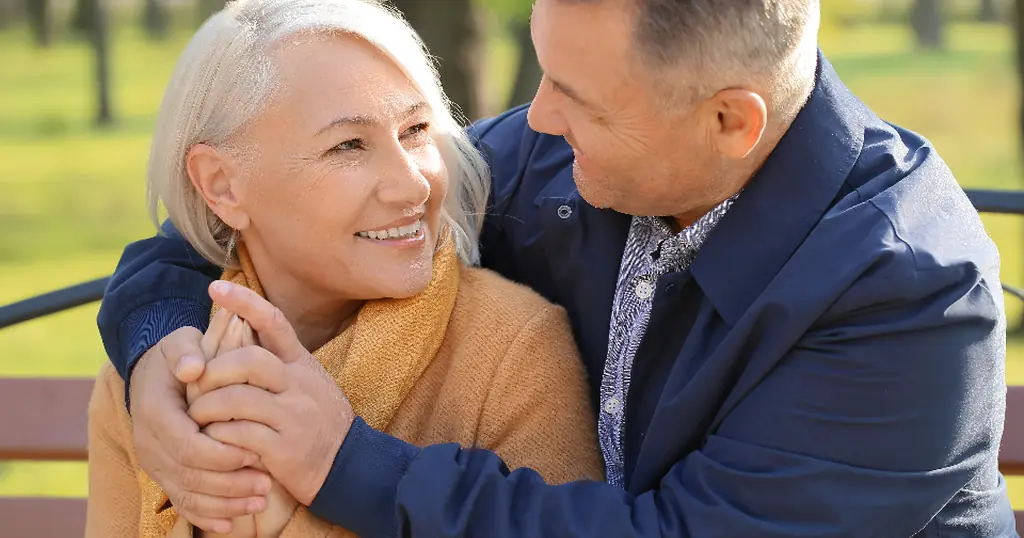 Datingsites 50 plus: een ouder koppel omhelst elkaar lachend op een bank